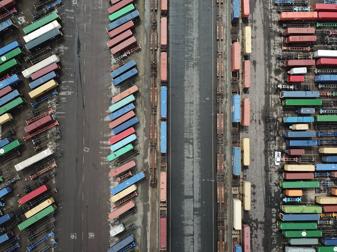 Aerial shot of colorful shipping containers lined up at a busy port terminal.